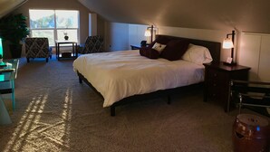 Een slaapkamer met een groot bed, twee nachtkastjes met lampen, een stoel, een klein tafeltje en een potplant.