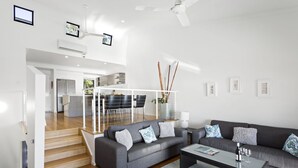 Una sala de estar moderna con un sofá gris, una mesa de centro y una escalera que lleva a una cocina.