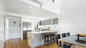 Cocina moderna con una isla central, electrodomésticos de acero inoxidable y un comedor con mesa y sillas.