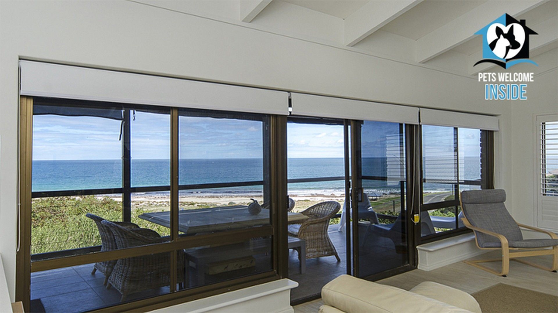 A spacious room with large sliding glass doors offering a view of the ocean and beach.