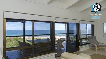 A spacious room with large sliding glass doors offering a view of the ocean and beach.
