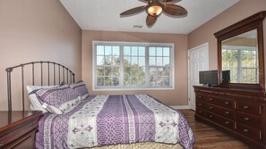 Quarto com cama, penteadeira e ventilador de teto.