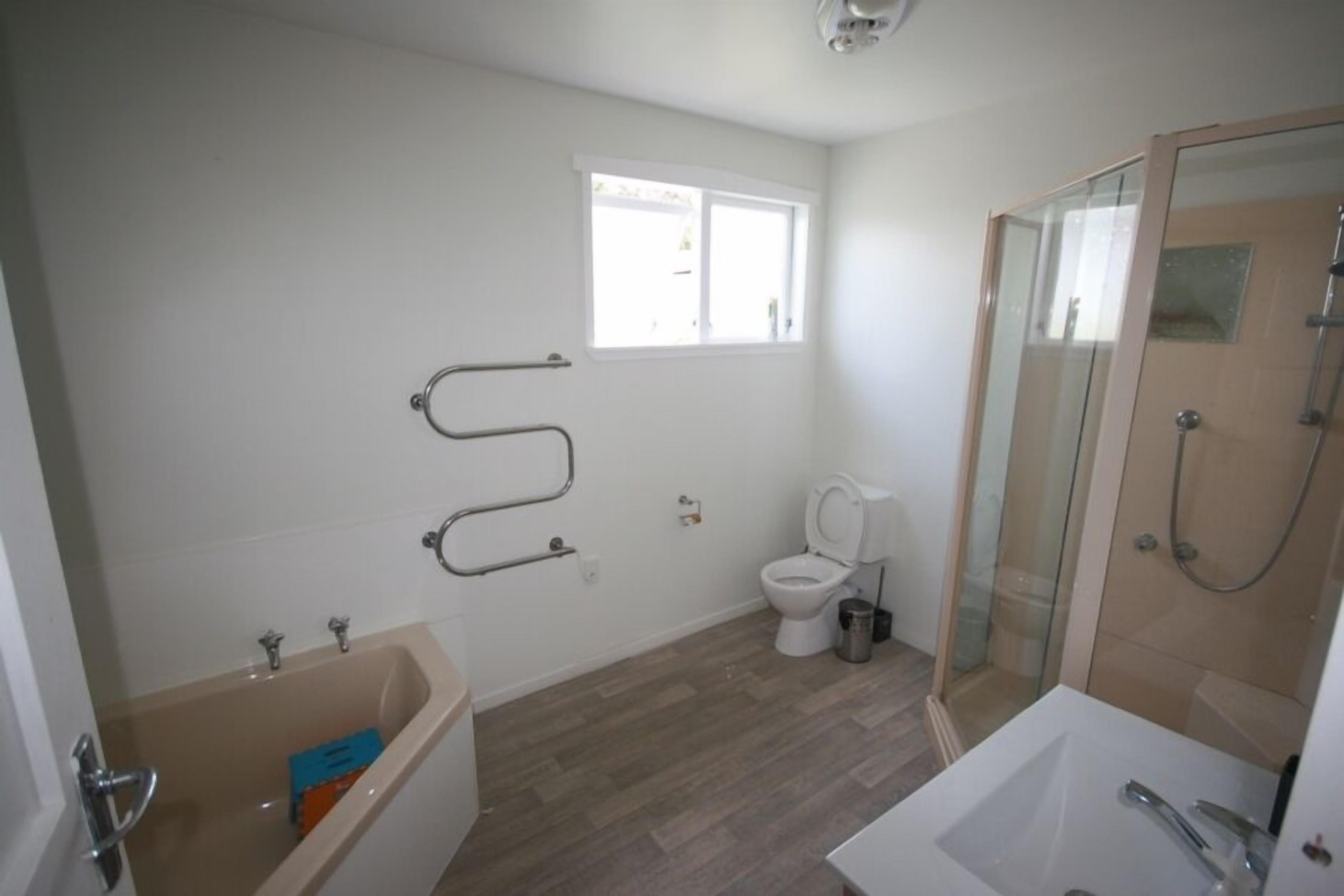 A bathroom with a bathtub, toilet, and shower area.