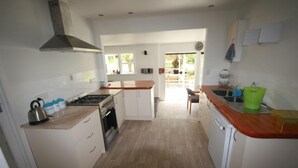 A compact kitchen with white cabinets, a wooden countertop, a stove, and a dishwasher.