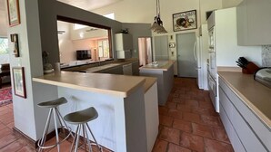 Une cuisine dotée d’un îlot central, de tabourets de bar, d’un luminaire suspendu et d’un réfrigérateur.