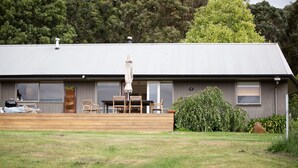 A modern house with a deck, outdoor furniture, and a large window.