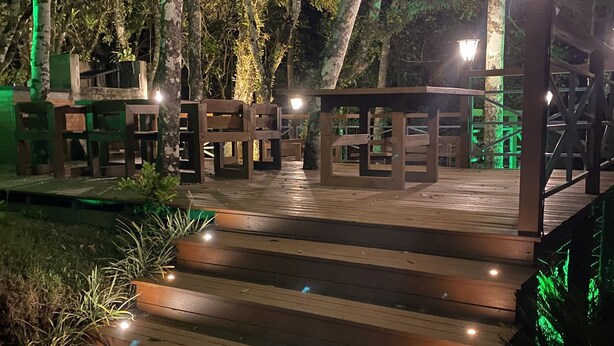 A wooden outdoor staircase with benches and a railing, surrounded by trees and illuminated by street lamps. - Comfort and Nature 1.2km from the Center of Gramado (Gramado)