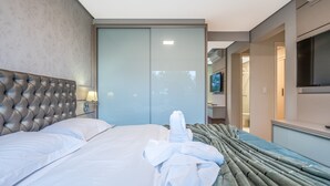 A hotel room with a large bed, a flat-screen TV, a minibar, and a sliding door to the bathroom. - Comfort and Nature 1.2km from the Center of Gramado (Gramado)