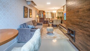 A modern living room with a sofa, ottoman, and a dining area with chairs and a table. - Comfort and Nature 1.2km from the Center of Gramado (Gramado)