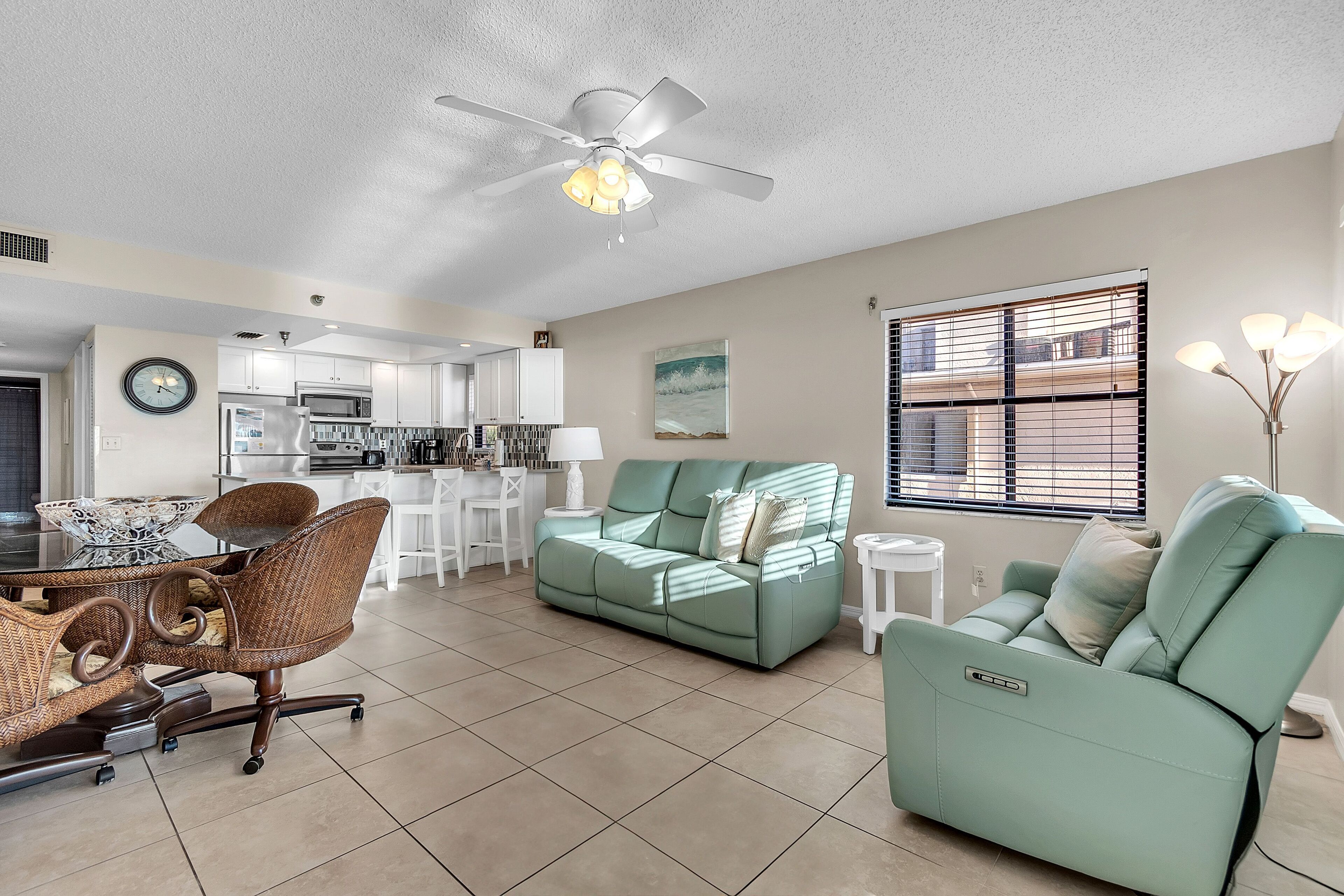 A spacious living area with a dining table, chairs, a sofa, and a ceiling fan.