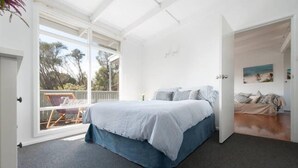 Ein Schlafzimmer mit Bett, großem Fenster und Blick ins Freie.