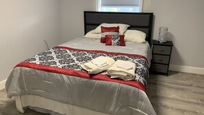 Una cama bien hecha con un edredón estampado, dos almohadas y dos toallas dobladas.