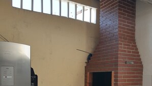 Una cocina compacta con un horno de ladrillo, un refrigerador y una pequeña mesa.