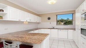 Cocina moderna con armarios blancos, encimera de granito y ventana con vistas al verdor.