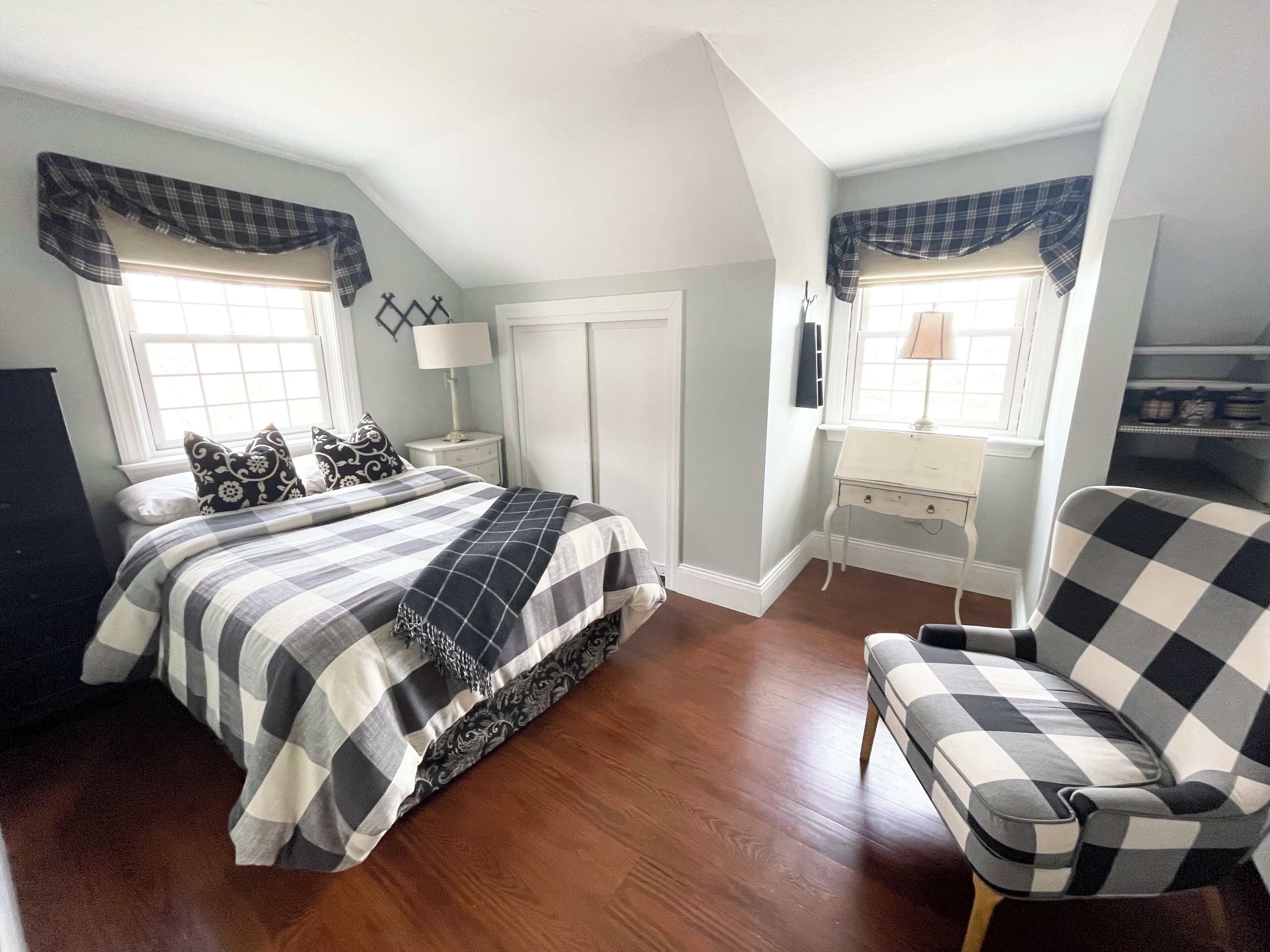 A bedroom with a bed, a chair, a desk, and a wardrobe.