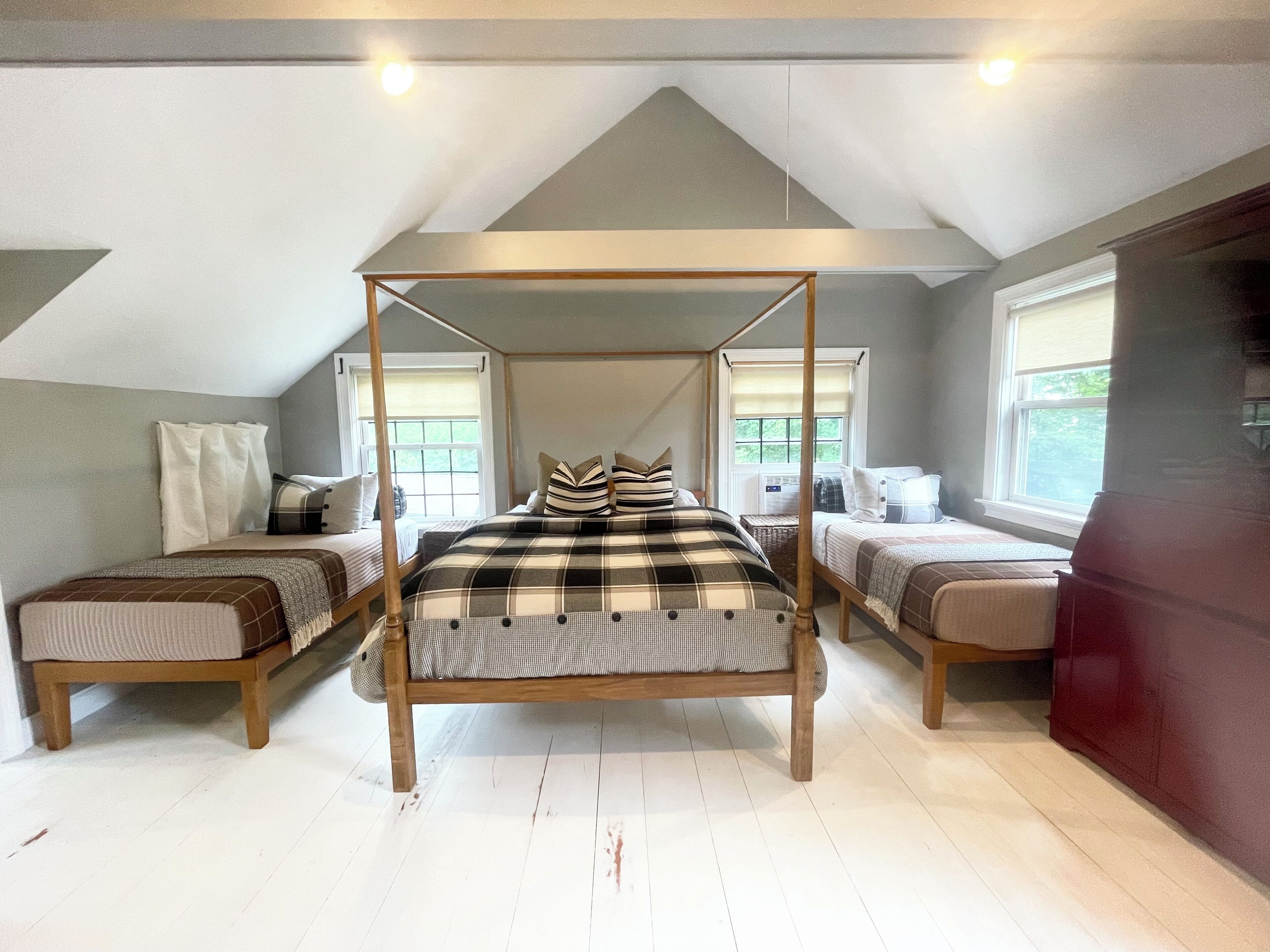 A bedroom with a four-poster bed, two bedside tables, and a window with a view.