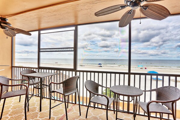 Un balcon doté de meubles en osier et offrant une vue sur la plage.