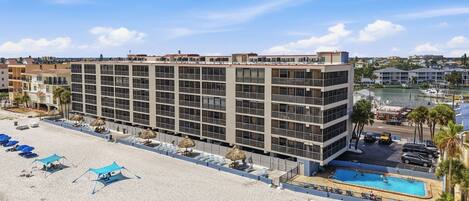 A multi-story hotel with a pool, beachside location, and a view of the marina.