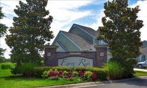Egrett Run features a modern design with a sloped roof and brick facade, set amidst beautifully maintained gardens.