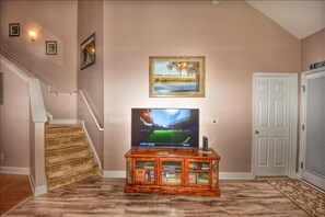 Stylish living area with a flat-screen TV, entertainment center, and a beautiful painting above.