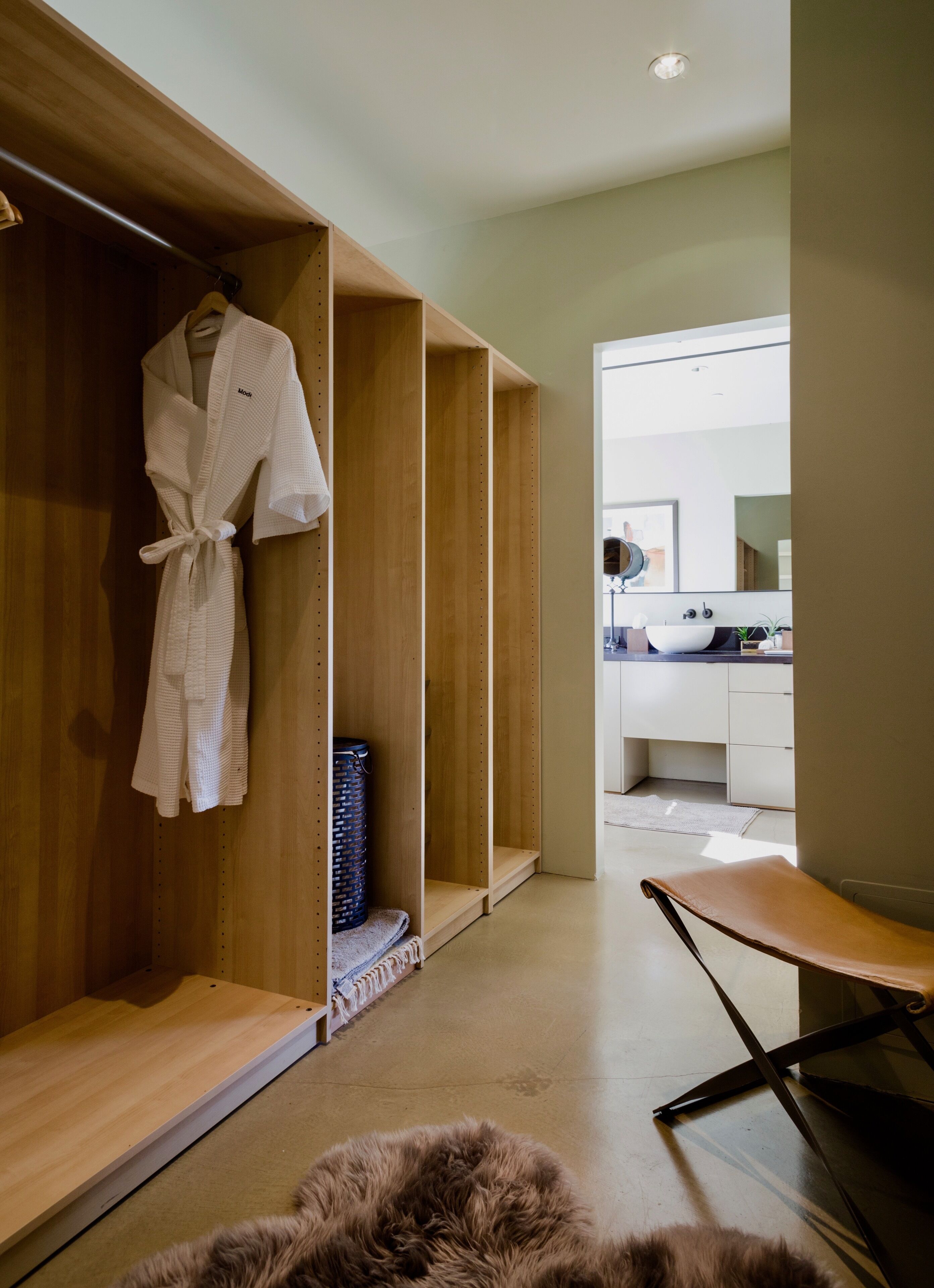 A modern bathroom with a wooden vanity, a mirror, and a sink.