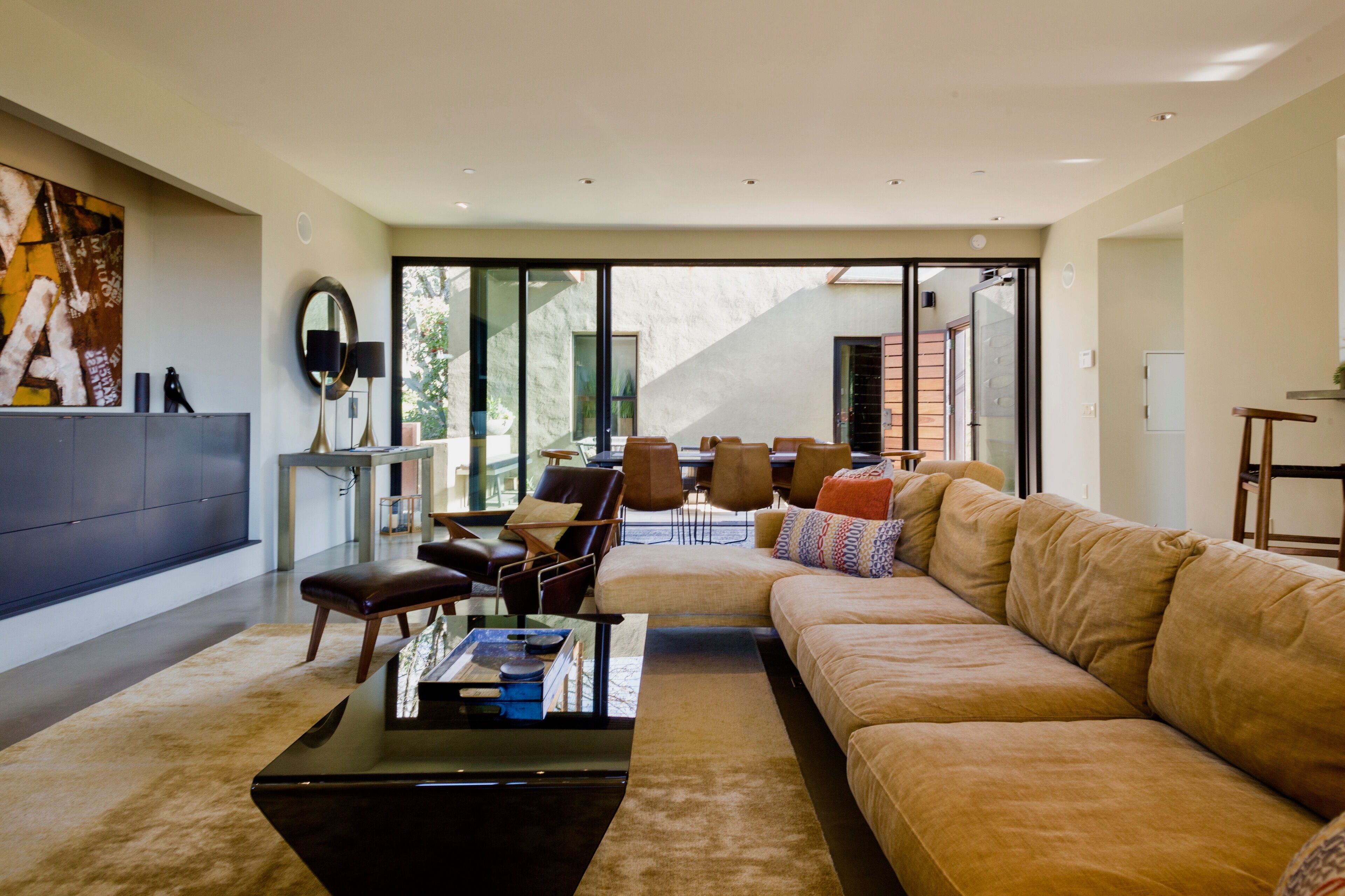 A modern living room with a large sofa, a coffee table, and a dining area with chairs and a table.