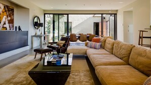 A modern living room with a large sofa, a coffee table, and a dining area with chairs and a table. - Modern Sonoma Home! Beautiful Views, Hot Tub.  Relax on The Patio, Wine Country! (Sonoma)