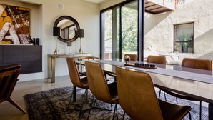 A modern dining area with a long table, leather chairs, a round mirror, and a large abstract painting on the wall. - Modern Sonoma Home! Beautiful Views, Hot Tub.  Relax on The Patio, Wine Country! (Sonoma)