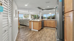 Eine moderne Küche mit Holzschränken, einem schwarzen Kühlschrank und einem Essbereich mit einer Couch.