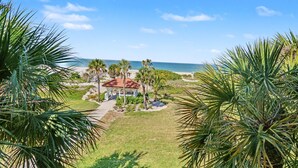 Blick auf einen Strand mit einer Laube, Palmen und blauem Himmel.