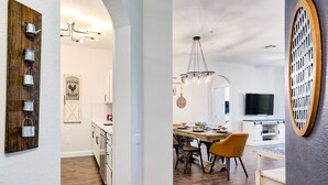 Een moderne keuken met een houten achterwand, een eethoek met een houten tafel en stoelen, en een aan de muur bevestigde televisie.