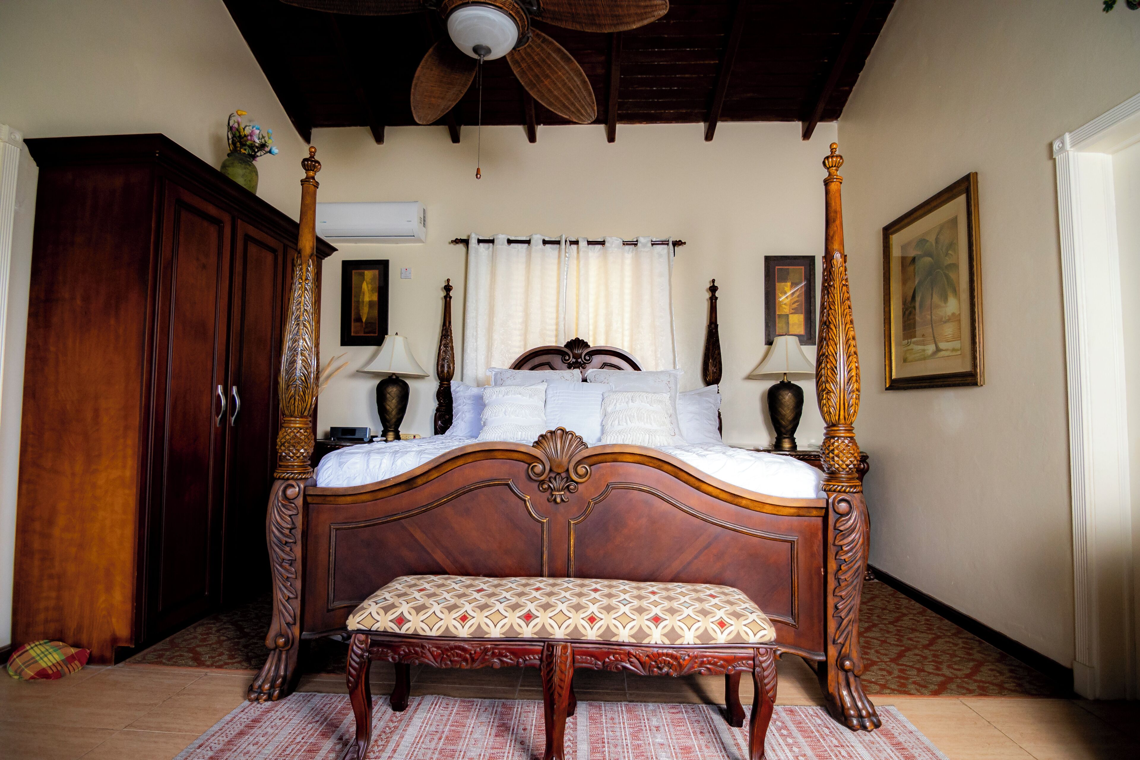 Ein Schlafzimmer mit einem Himmelbett, Holzmöbeln und einem Deckenventilator.