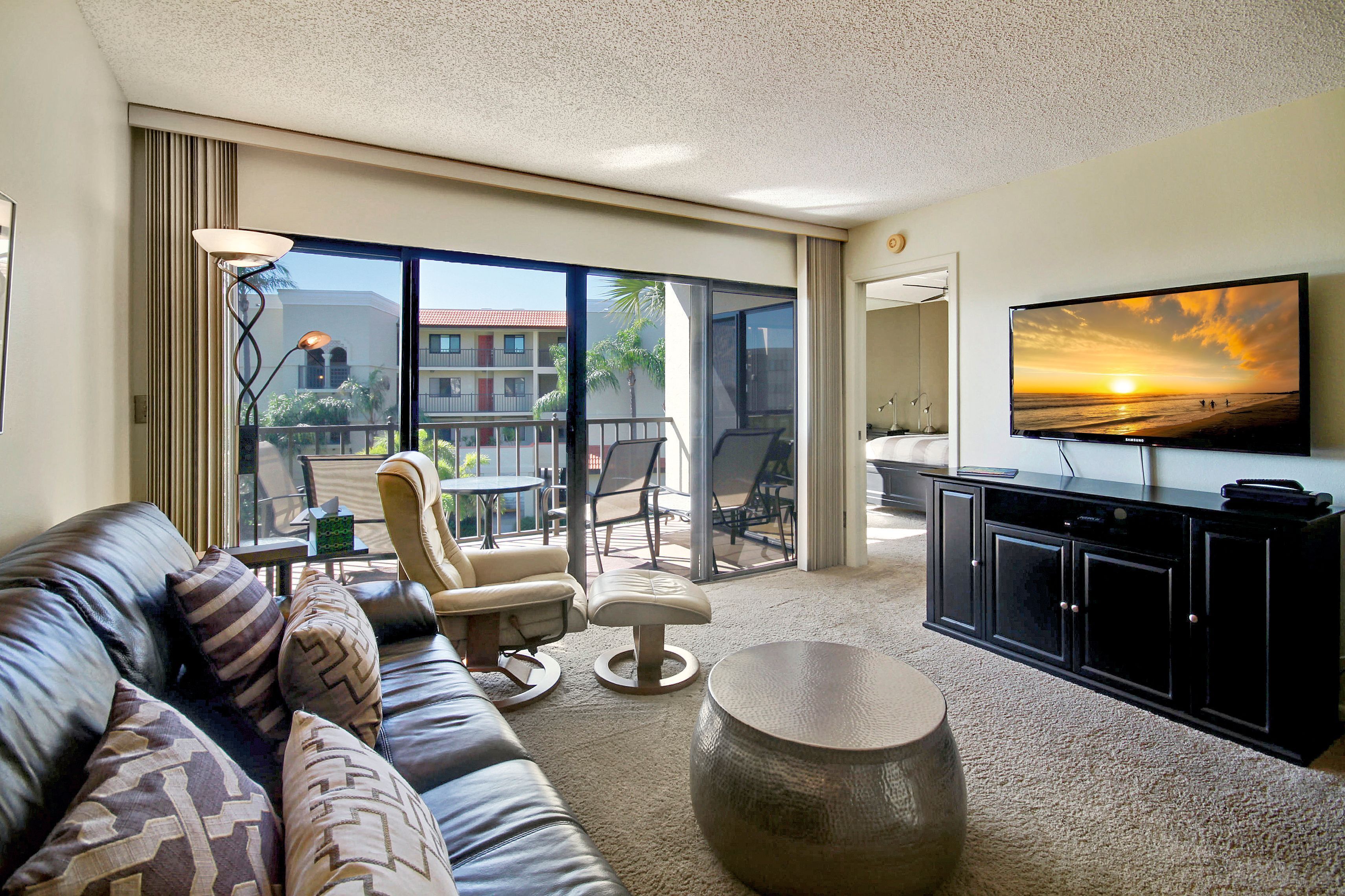 A modern living room with a leather sofa, a round coffee table, and a flat-screen TV mounted on the wall.