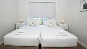 Habitación doble con dos mesitas de noche, cada una con una lámpara, y almohadas con forma de estrella.