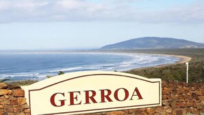 Vista costera con un cartel que dice "GERROA" frente a un muro de piedra.