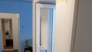 Een wasserij met een wasmachine en droger, houten vloeren en een witte koelkast.