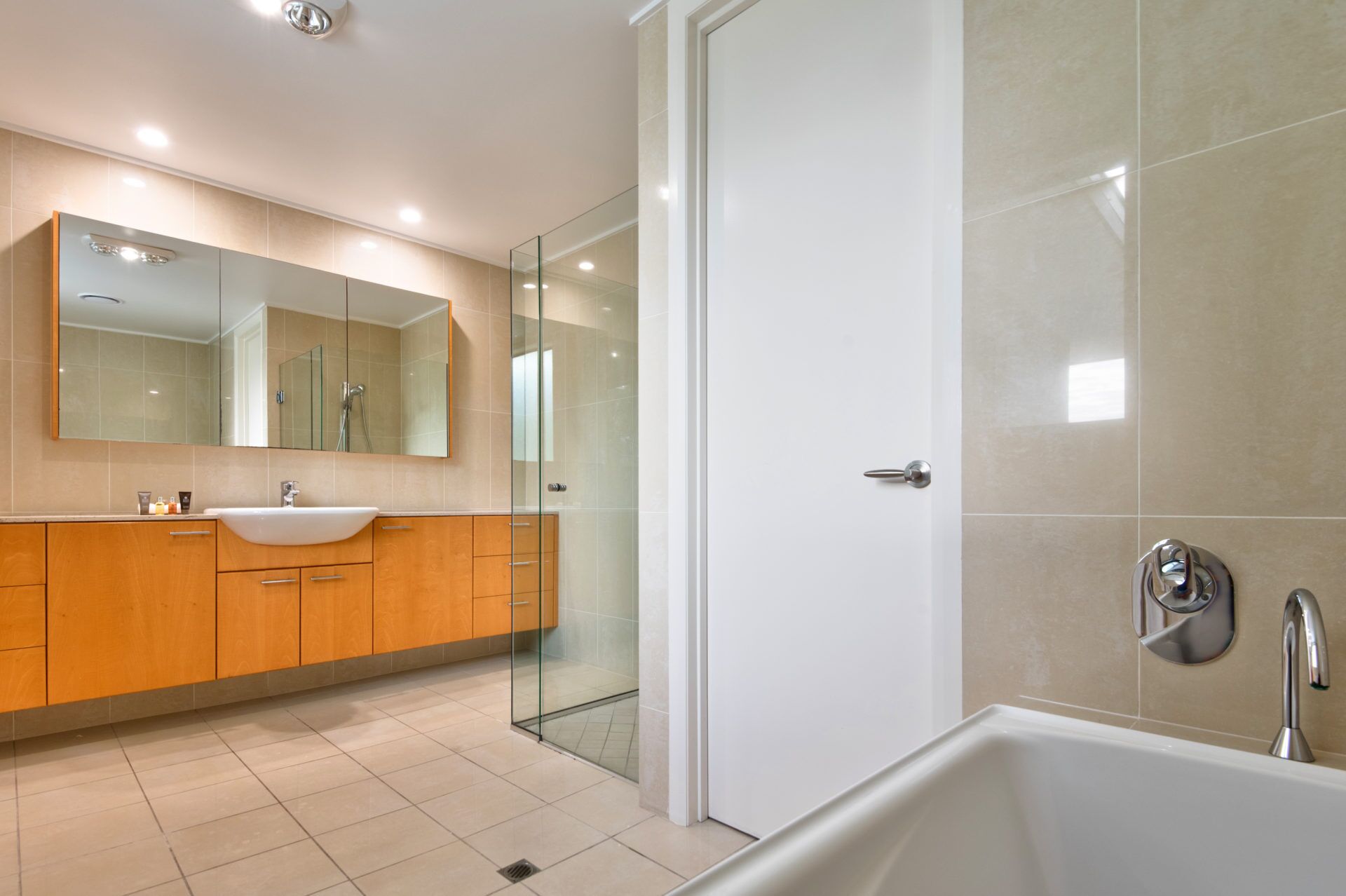 Un baño moderno con un espejo grande, un lavabo y una zona de ducha.