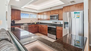 Una cocina moderna con gabinetes de madera, electrodomésticos de acero inoxidable, encimera de granito y horno empotrado.