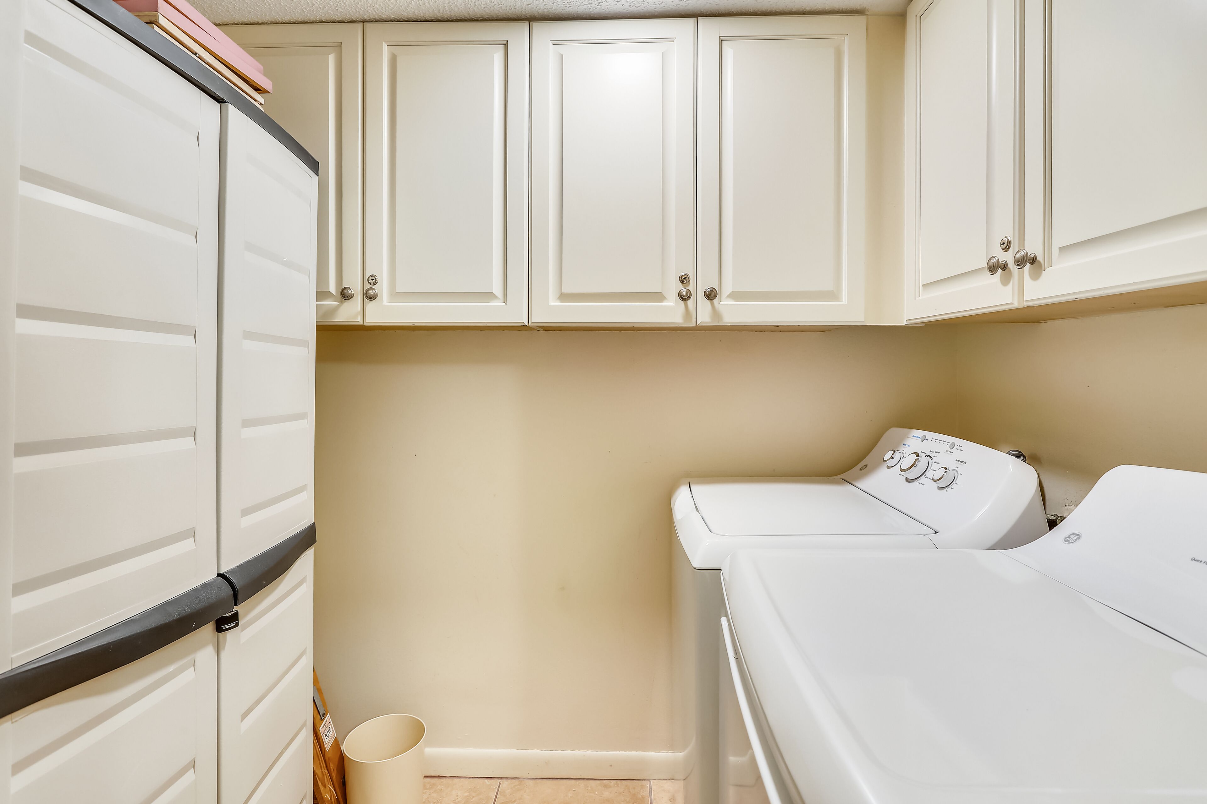 A laundry room with a washing machine, a dryer, and cabinets.