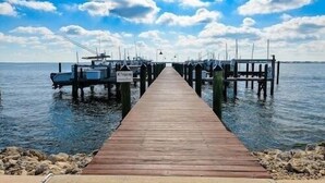 A wooden pier extending into calm water, with boats docked on either side. - Close to Beach, 3 Bed, 2 Bath, Comun. Dock, New Remod! Community Pool! (Jensen Beach)