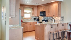 Eine moderne Küche mit Holzausstattung, Granit-Arbeitsplatten, einer integrierten Mikrowelle und einer Kaffeemaschine.