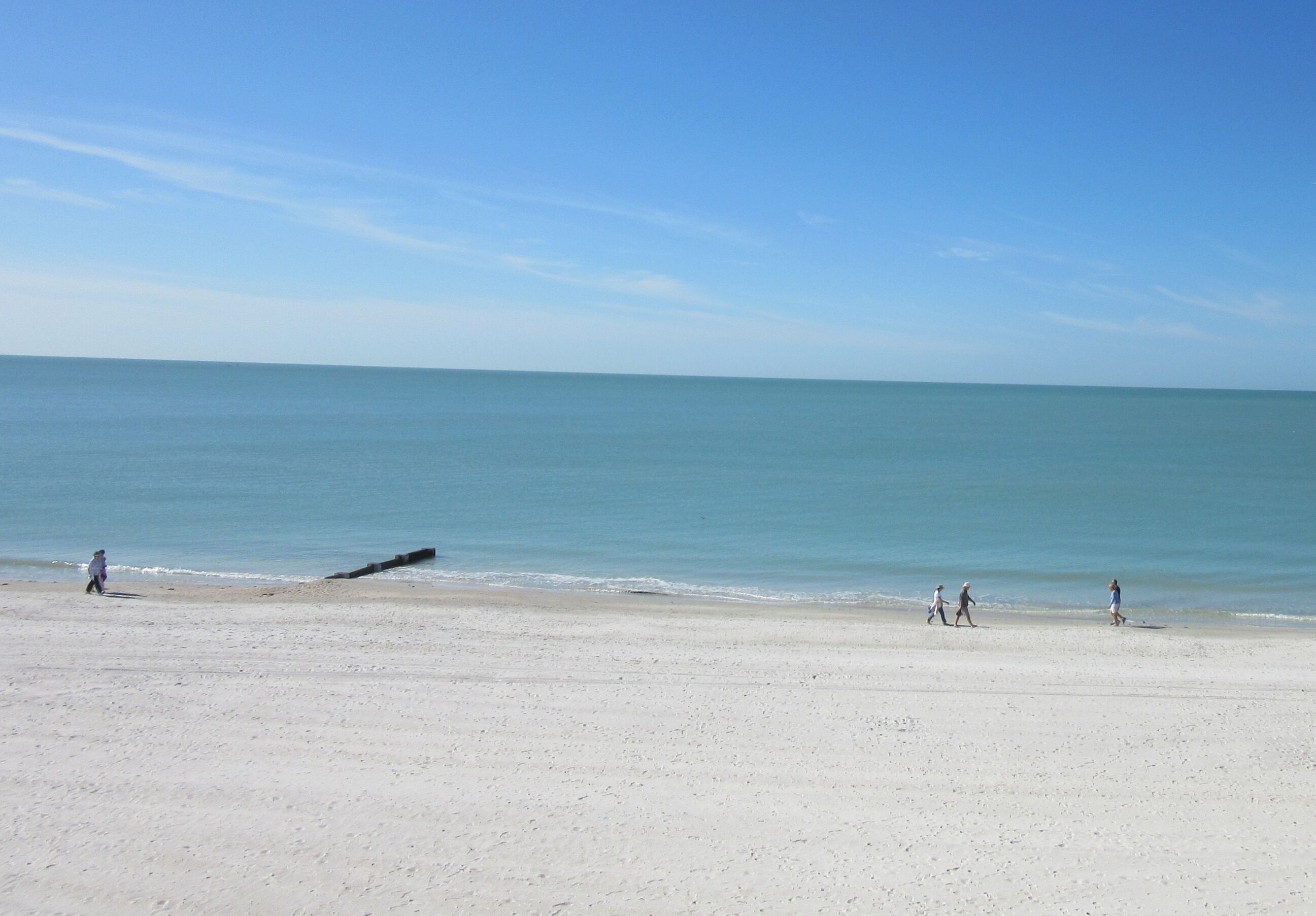 Uma praia com céu claro e mar calmo.
