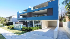 A modern two-story house with a flat roof, large windows, and a visible garage.