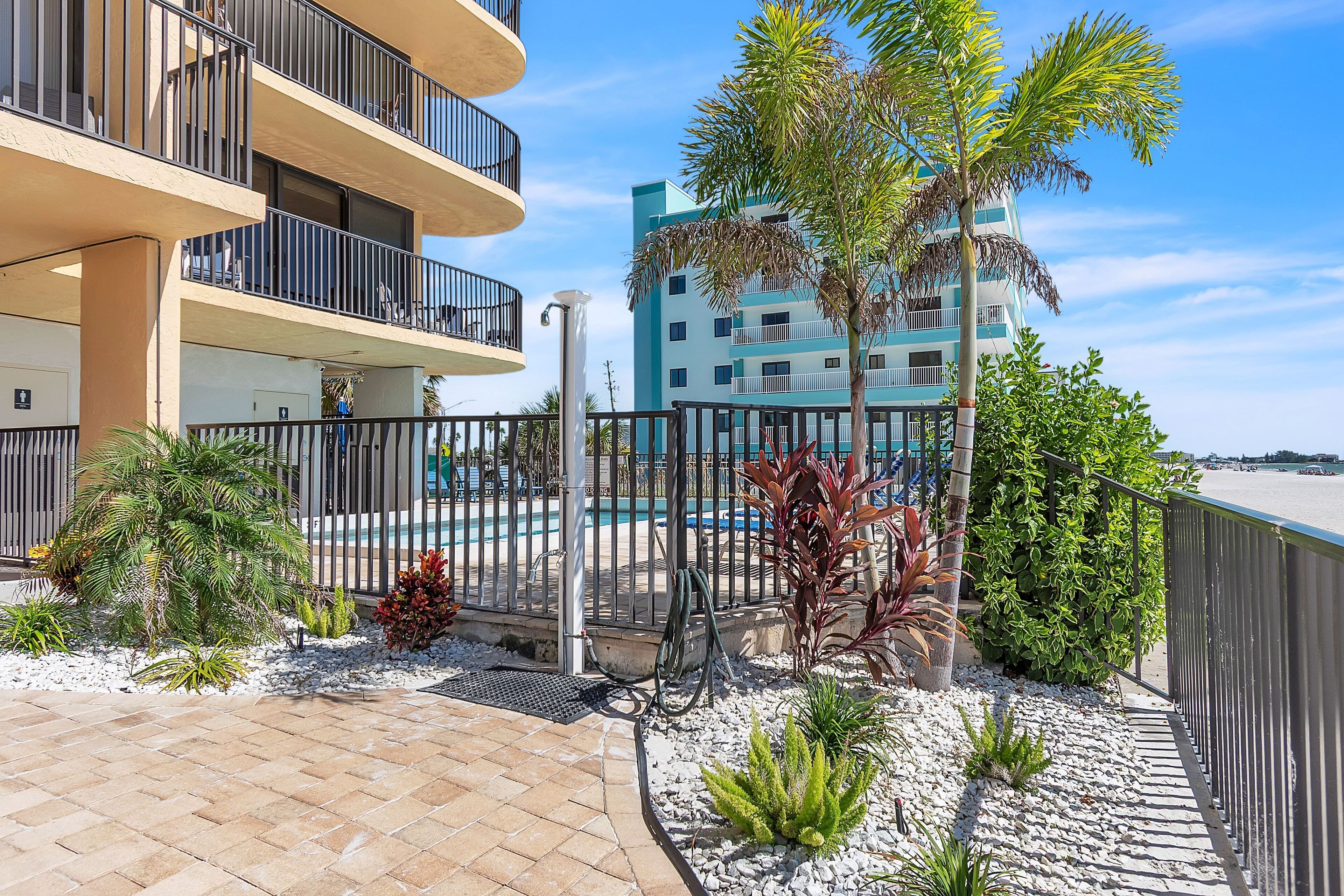 A multi-story hotel with balconies, a swimming pool, and a beach view.