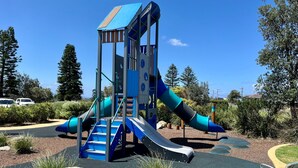 Une aire de jeux avec un toboggan, une zone d’escalade et une structure de jeu abritée.