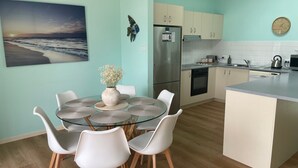 Une cuisine moderne dotée d’un îlot central, de meubles blancs et d’un réfrigérateur en acier inoxydable.
