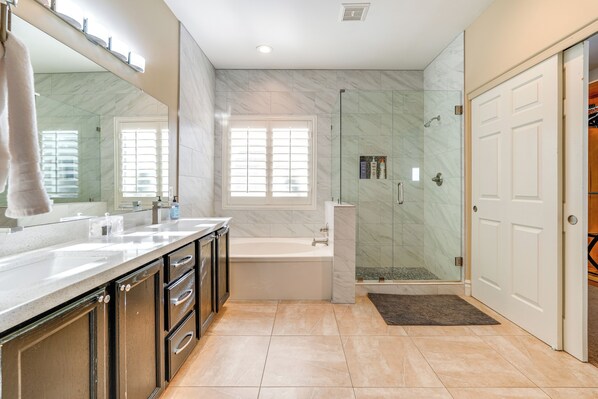 Une salle de bain moderne dotée d’un grand miroir, d’une baignoire, d’une cabine de douche et d’un meuble-lavabo avec des tiroirs.