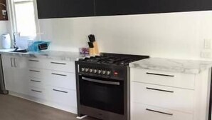 A modern kitchen with white cabinets, a black stove, and a window. - Bella Vita @ Yarrawonga (Yarrawonga)