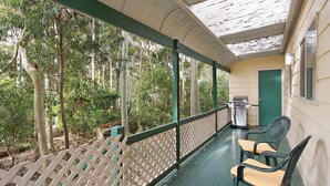 An outdoor deck with a grill, chairs, and a door. - Beachwood  on  Casey (Mystery Bay)