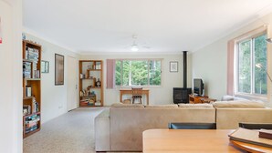 A cozy living room with a sofa, a wooden table, and a bookshelf filled with books. - Beachwood  on  Casey (Mystery Bay)
